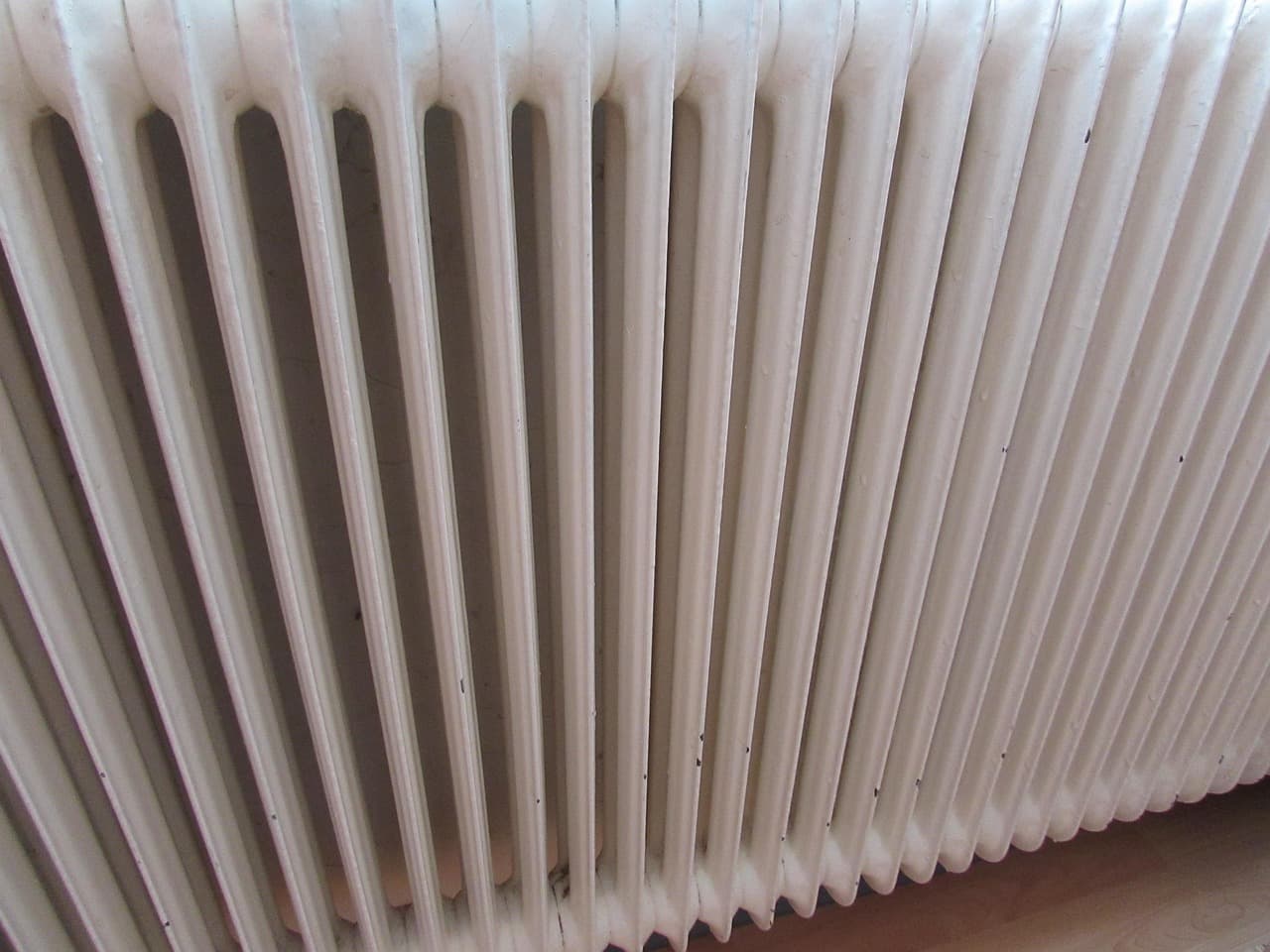 A white column radiator against a pale wall